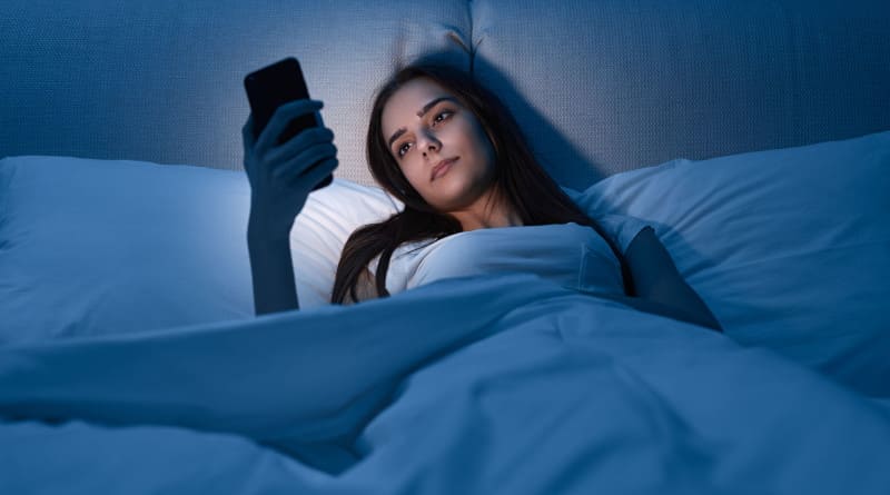 Foto jovem mulher com smartphone deitada na cama