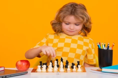 Foto criança brincando de xadrez no fundo do estúdio criança jogando xadrez pensando jogo de xadrez infantil para crianças