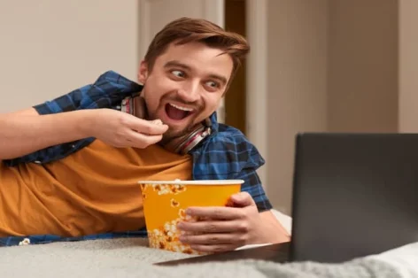 Foto homem animado comendo pipoca e assistindo filme