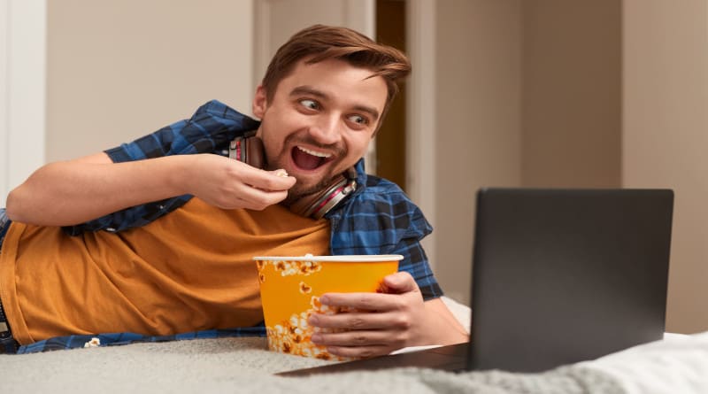 Foto homem animado comendo pipoca e assistindo filme