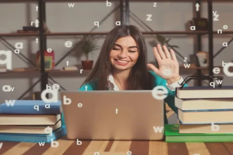 Foto linda mulher está feliz com seu trabalho bem sucedido com laptop cinza e livros na mesa de madeira