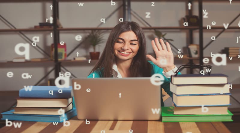Foto linda mulher está feliz com seu trabalho bem sucedido com laptop cinza e livros na mesa de madeira