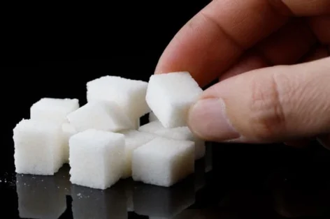 Foto pedaços de açúcar na mão sobre uma superfície preta