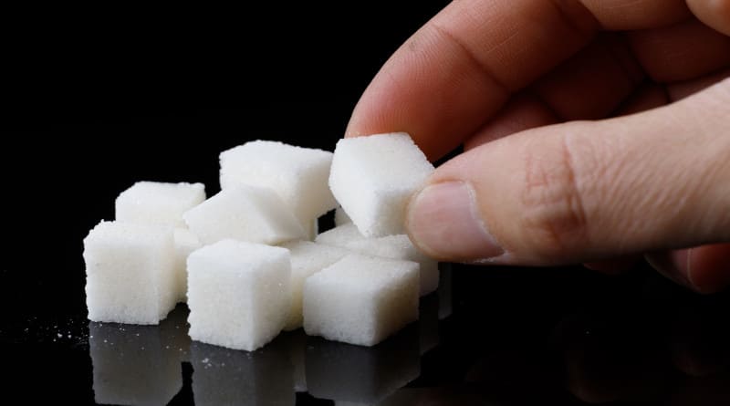Foto pedaços de açúcar na mão sobre uma superfície preta