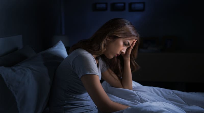 Foto de uma jovem asiática deprimida sentada na cama não consegue dormir por causa da insônia