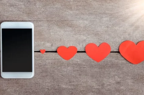 Foto de smartphone e papel de corações em fundo de madeira