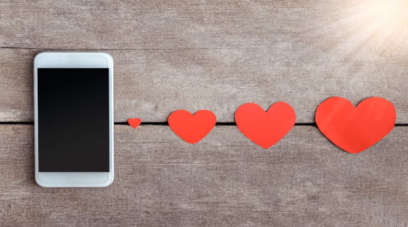 Foto de smartphone e papel de corações em fundo de madeira