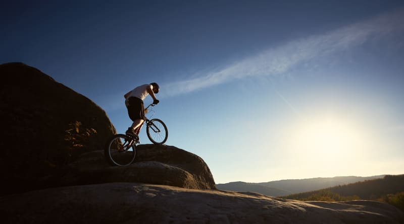 Foto ciclista profissional equilibrando-se na bicicleta experimental ao pôr do sol