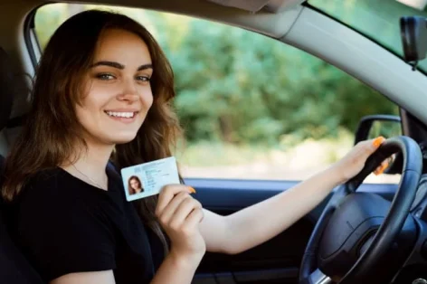 Foto de uma jovem em um carro moderno mostrando carteira de motorista