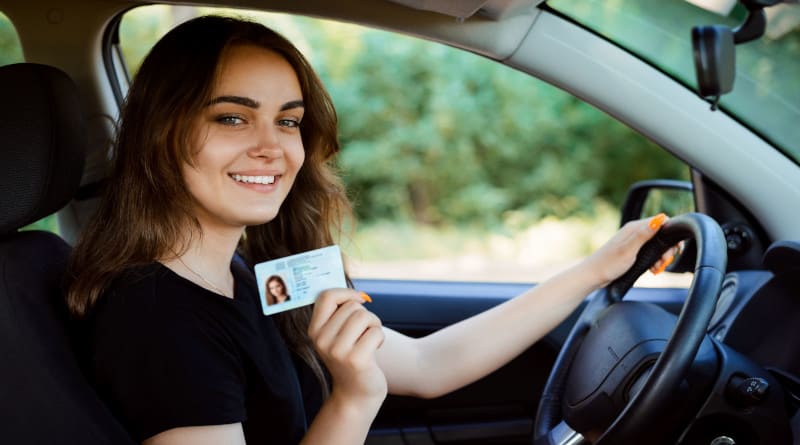 Foto de uma jovem em um carro moderno mostrando carteira de motorista
