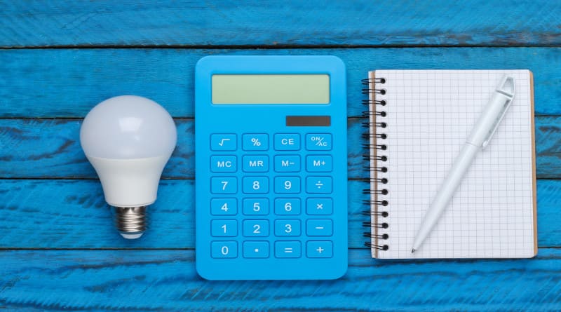 Foto economizando eletricidade. lâmpada led e calculadora, caderno na superfície de madeira azul. vista do topo