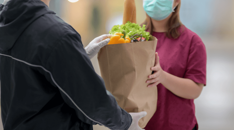 Foto de cliente feminina recebendo sacola de comida fresca do entregador em sua casa