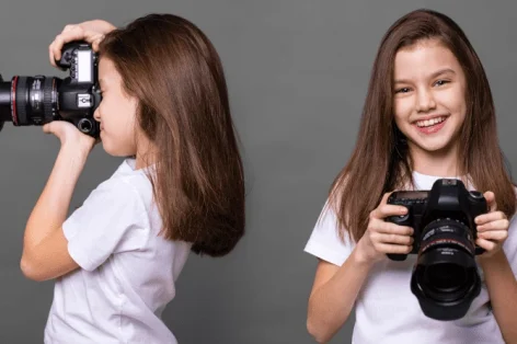 Photo cute brunette little girls holding an photo camera isolated on gray background