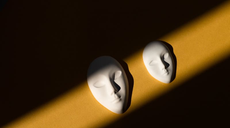 Foto máscara branca com expressão facial neutra com sombras em fundo dourado