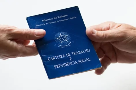 Foto mão segurando carteira trabalhista brasileira.