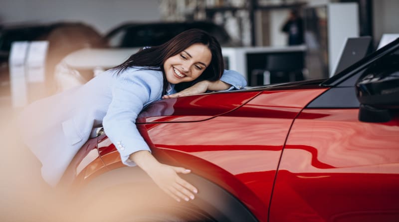 Foto de mulher abraçando seu novo carro vermelho