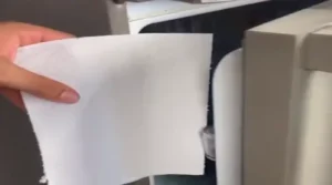 Folha de papel toalha sendo inserida na porta da geladeira