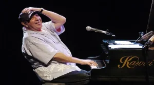 Foto do Compositor João Donato sorrindo sentado ao piano