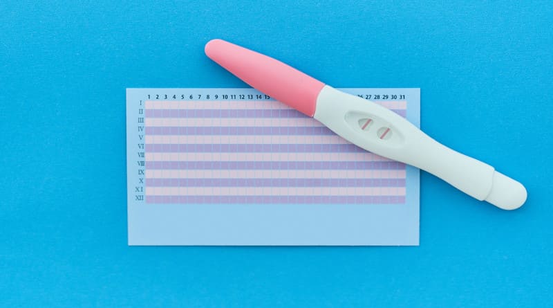 Foto positiva de teste de gravidez de duas listras com calendário do período de ovulação