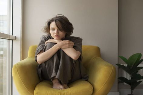 Foto completa de uma mulher com ansiedade sentada na cadeira