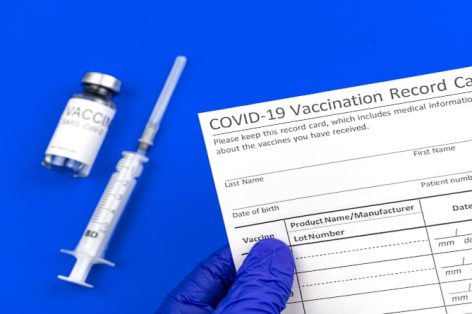 Cartão de registro de vacinação contra coronavírus fotográfico, documento oficial na mão do médico close-up