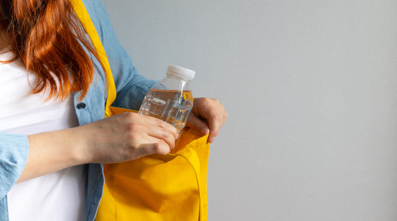 jovem camisa branca tira água de garrafa de plástico do saco amarelo