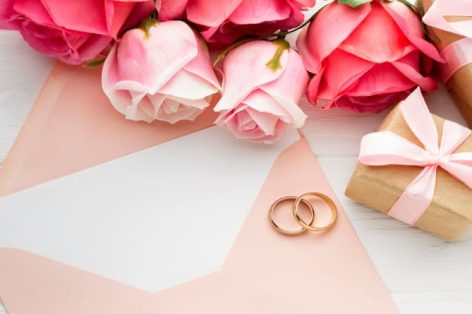 Pink roses and wedding rings on envelope