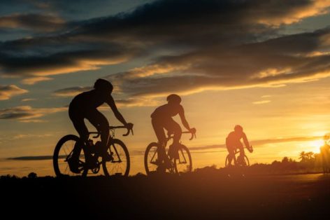 Foto traseira de ciclistas andando de bicicleta no fundo da hora do pôr do sol