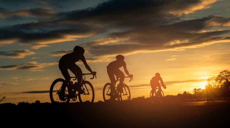 Foto traseira de ciclistas andando de bicicleta no fundo da hora do pôr do sol