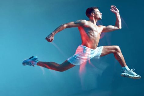 Foto de retrato de corpo inteiro vista lateral de um cara de fitness correndo um jovem seminu de short branco em azul