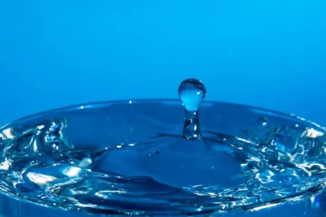 Foto gota de água caindo em um copo, atingindo a superfície da água.foco selecionado