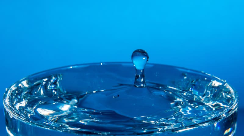 Foto gota de água caindo em um copo, atingindo a superfície da água.foco selecionado