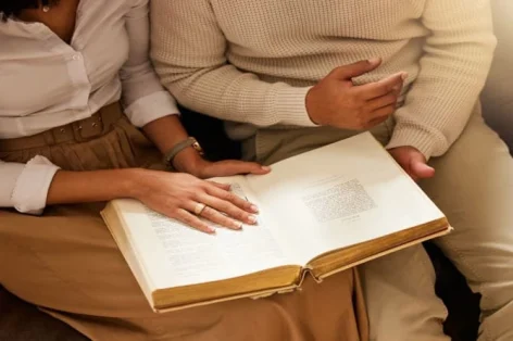Mãos da Bíblia e leitura com um casal negro juntos em sua casa para religião, fé ou crença em Deus Jesus ora ou livro com um homem e uma mulher cristãos aprendendo sobre o cristo espiritual
