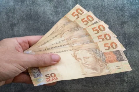 Mão segurando notas de cinquenta reais dinheiro brasileiro